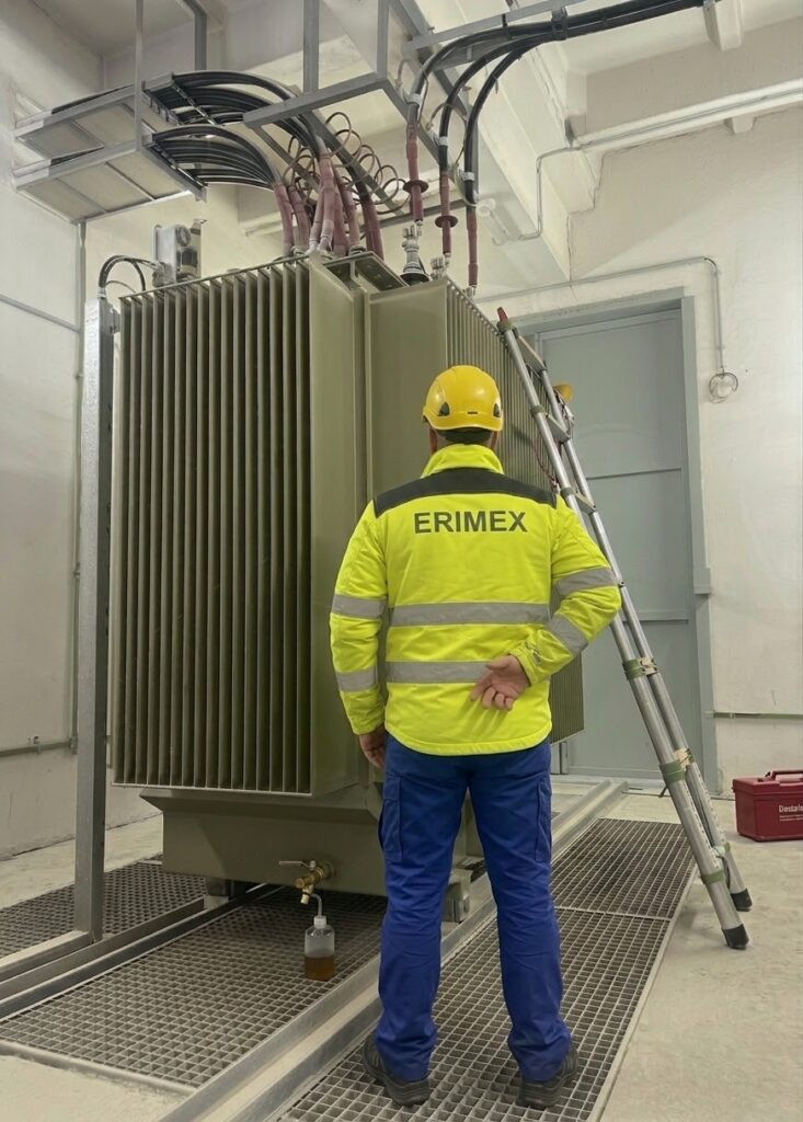 Revízny technik ERIMEX v ochrannom odeve pri odbornej prehliadke transformátora vo vysokonapäťovej rozvodni